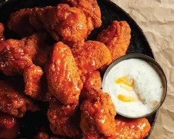 A basket of sauced chicken wings with celery